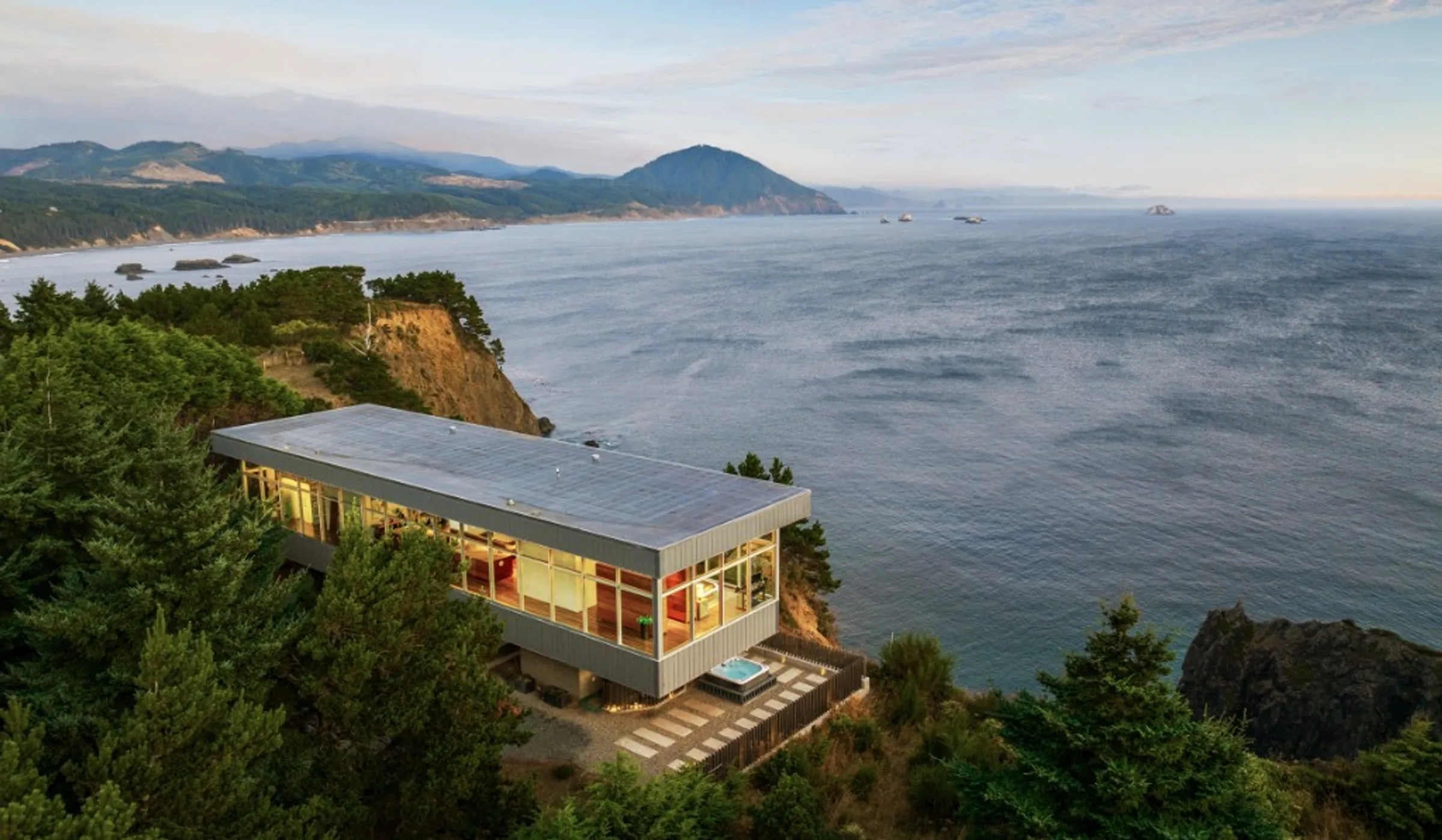 A glass home on a cliff above the ocean